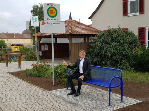 Bürgermeister Ulrich Werner sitzt auf der neuen Mitfahrbank in Garstadt